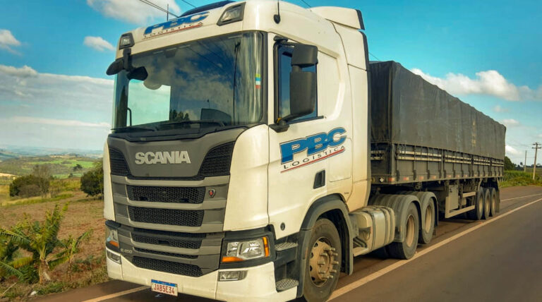 Caminhão scania branco r450 da PBC estacionando na rodovia