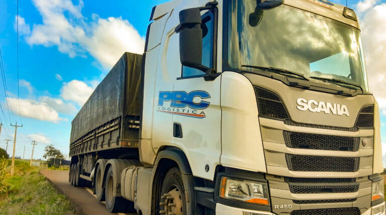 Caminhão scania branco r450 da PBC estacionando na rodovia